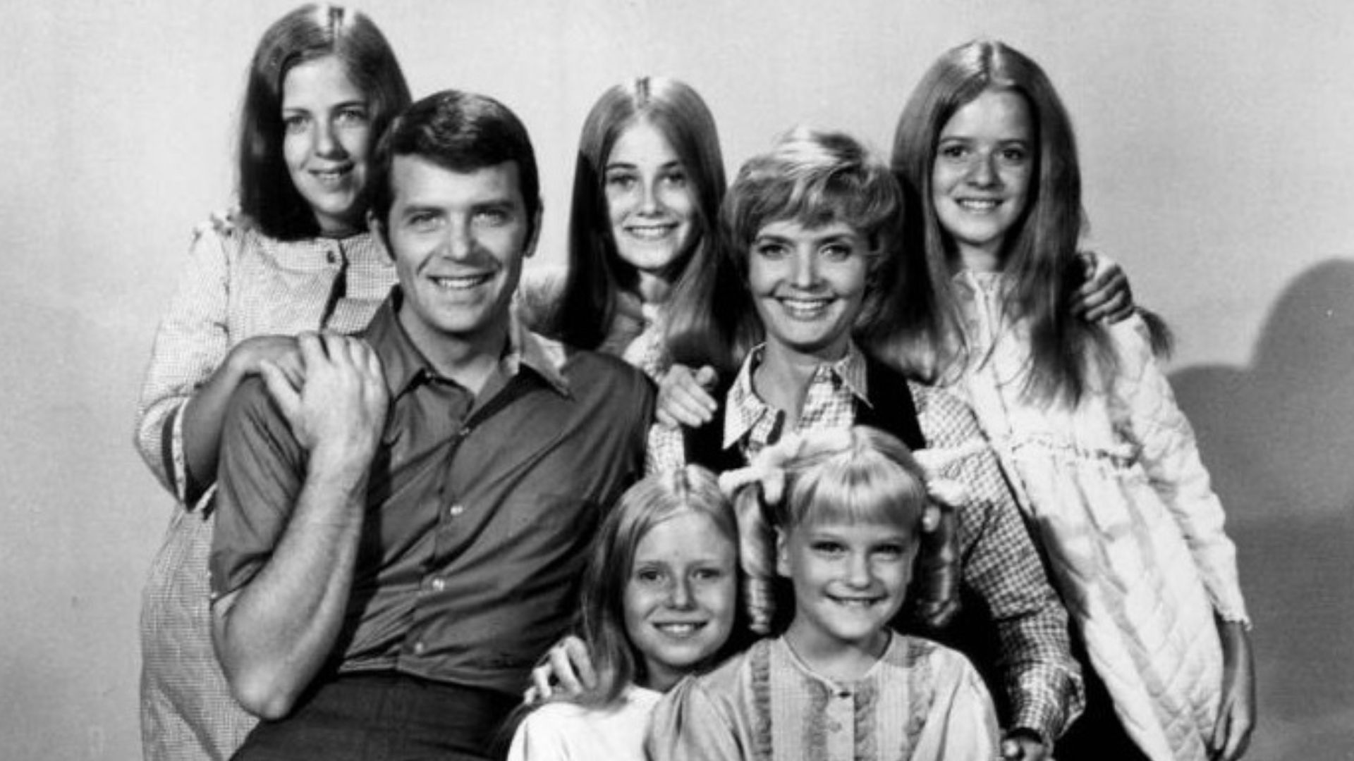 Publicity photo of American actors, (front row; sitting; L–R) Eve Plumb, Susan Olsen, (second row; sitting; L–R) Robert Reed, Florence Henderson, (back row; standing; L-R) Carolyn Reed, Maureen McCormick and Barbara Henderson Bernstein promoting the Octob