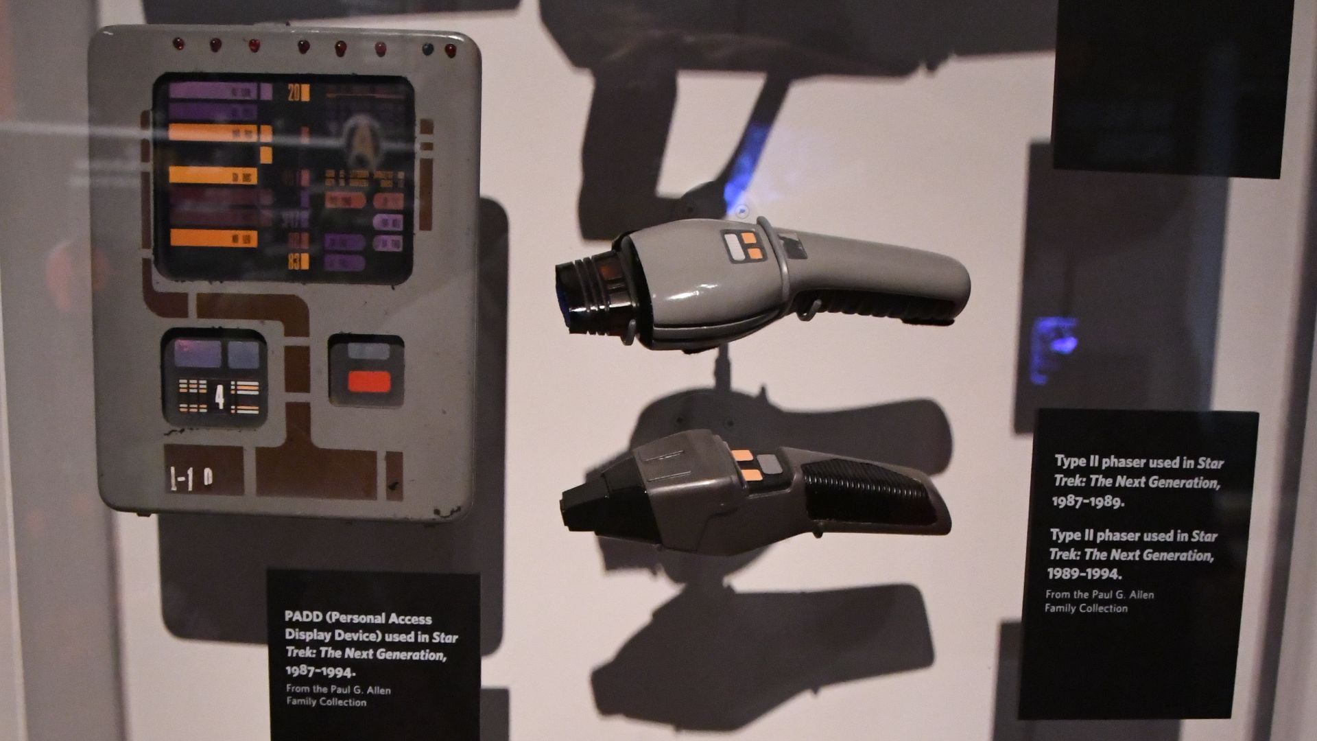 Various props from Star Trek: The Next Generation. Props include an alien rifle (top), two different Type II phasers in he center (the top one is 1987-1989, the lower is 1989-1994), a computer panel (lower right), a Romulan distruptor pistol (lower left),