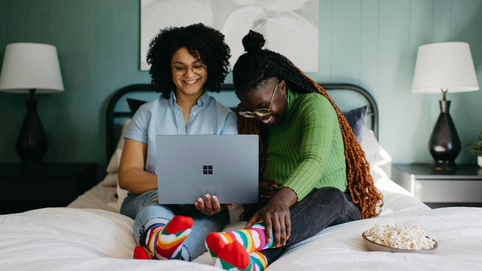 a woman sitting on a bed using a laptop