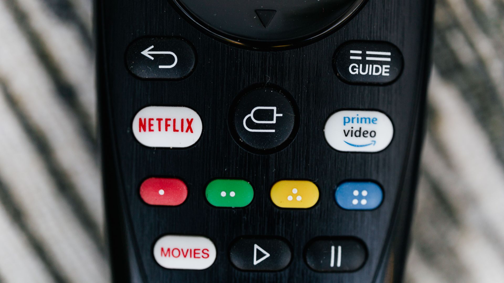 Detailed close-up image of a TV remote control with streaming service buttons.
