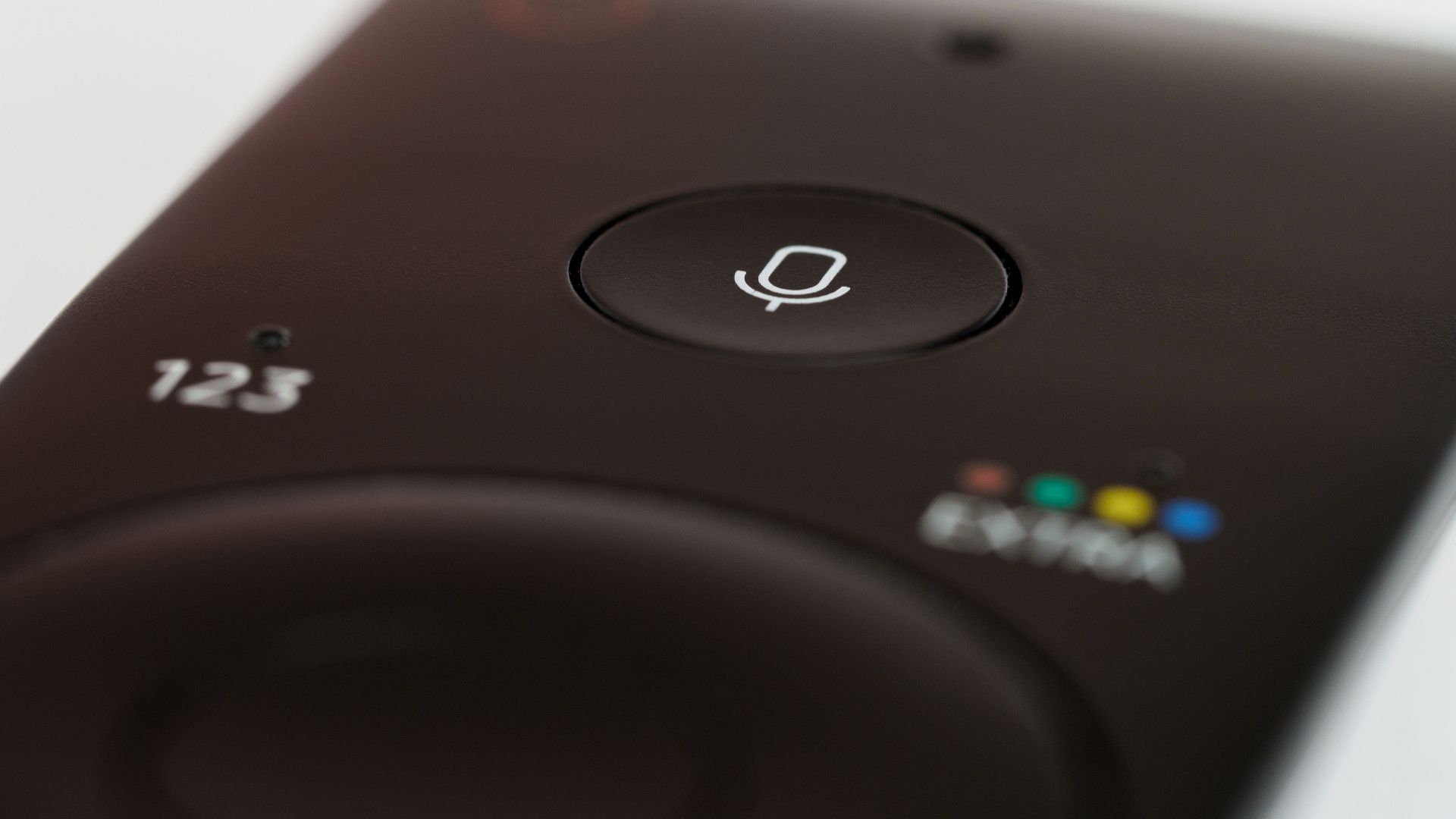 Close-up of a remote control featuring a prominent microphone button, suitable for voice commands.
