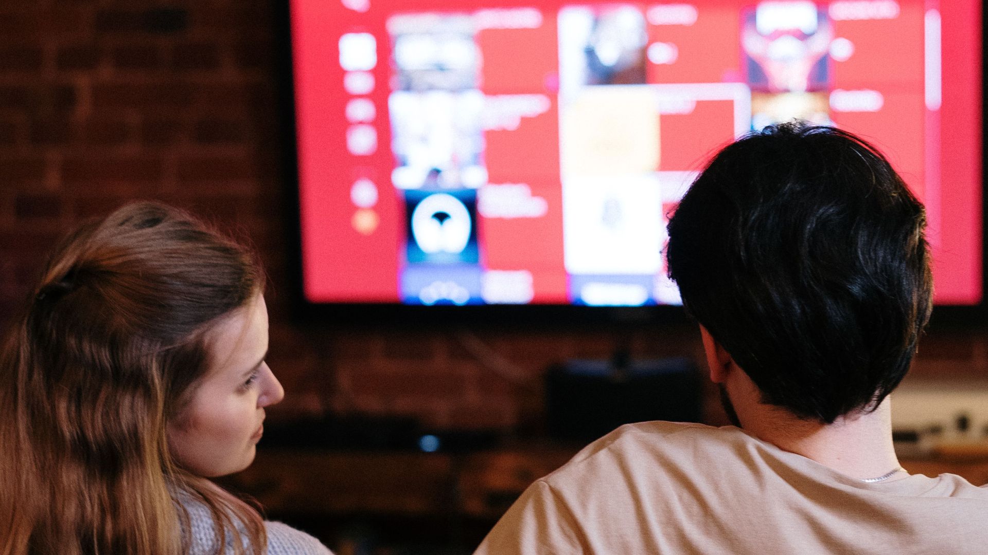 A couple sitting together in a cozy living room, watching a movie on a smart TV.