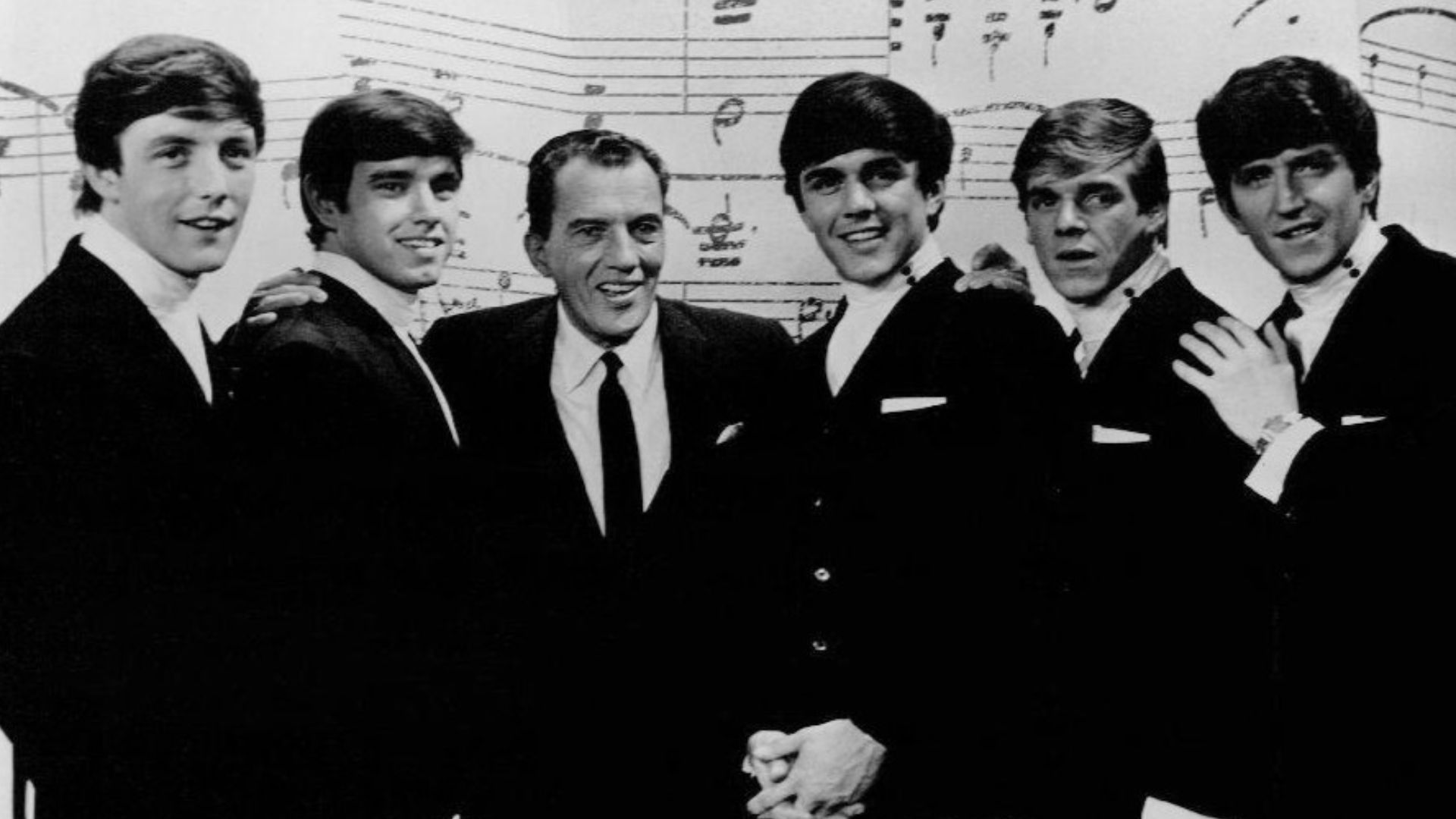 Photo of The Dave Clark Five with Ed Sullivan from an appearance on Sullivan's show.  From left: Mike Smith, Denny Payton, Ed Sullivan, Dave Clark, Lenny Davidson, Rick Huxley.