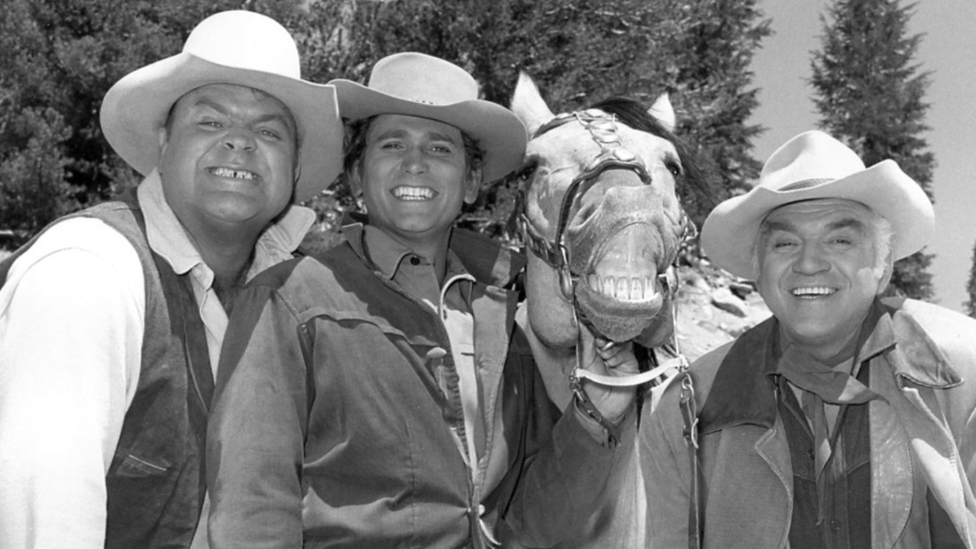 Photo of the main cast of Bonanza.  From left, Dan Blocker (Hoss), Michael Landon (Little Joe), Buck (Lorne Greene's horse in series), Lorne Greene (Ben).  Greene's horse decided to join the photo with a smile of his own accord.