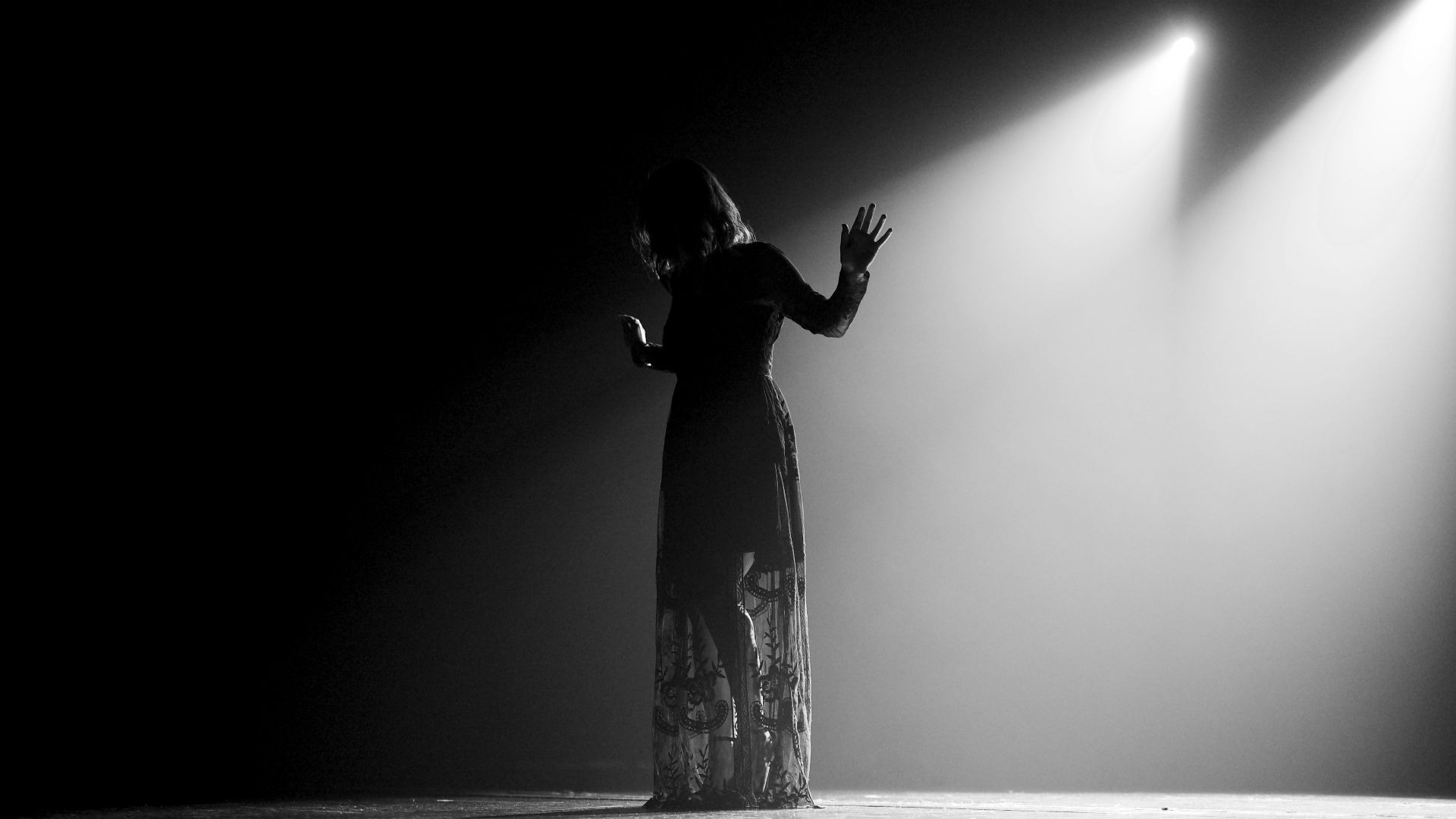 woman in black dress standing on stage