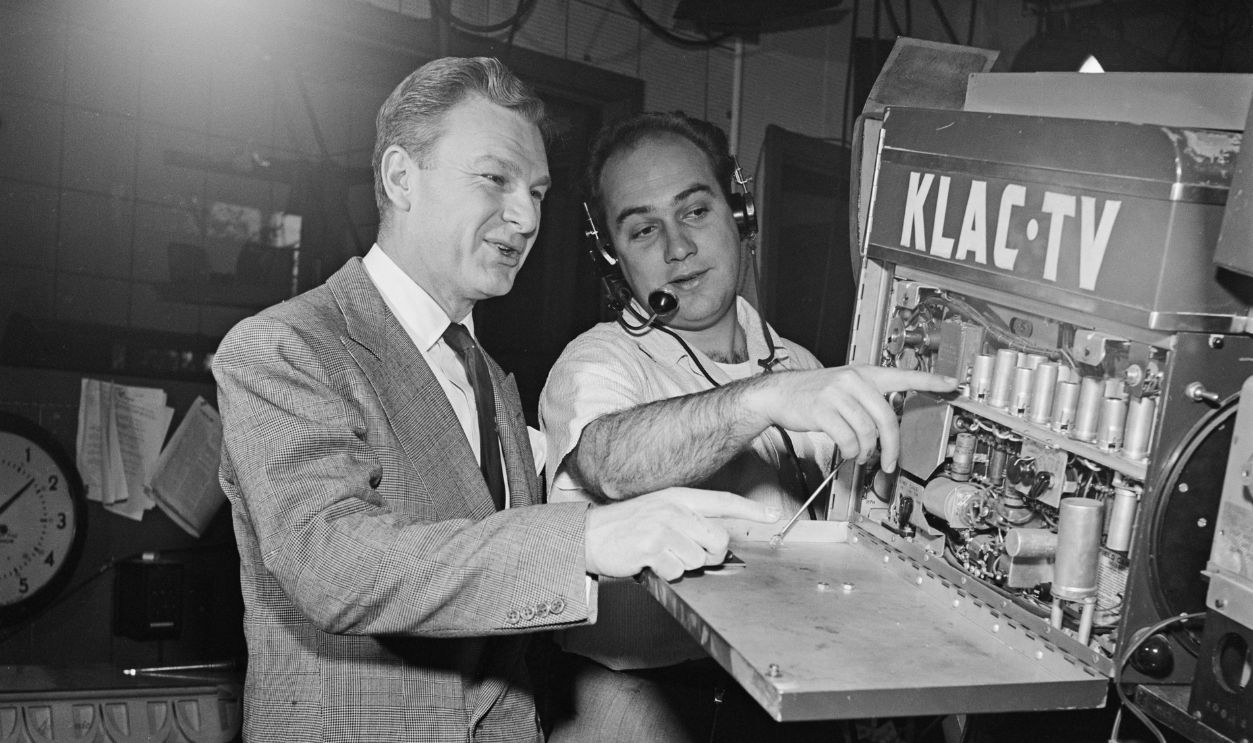 American actor Eddie Albert (1906 - 2005, left) chats with a technician at KLAC-TV, USA, circa 1952.