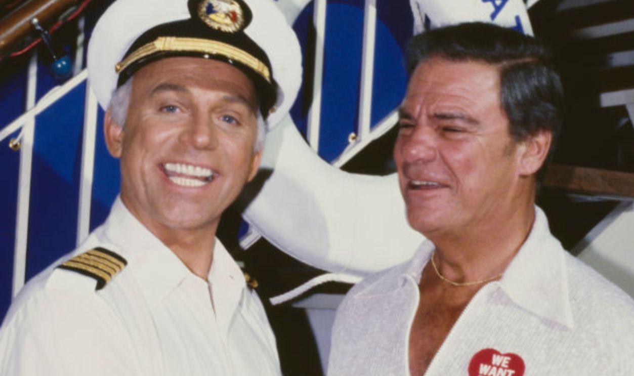 American actors Gavin MacLeod (1931 - 2021) and Bert Parks (1914 - 1992) promoting the latter's guest appearance in the series 'The Love Boat' at the studios of 20th Century Fox in Hollywood, California, January 11th 1980. MacLeod, who plays ship's captain Merrill Stubing in the show, pins a 'We Want Bert' badge onto Parks's shirt.