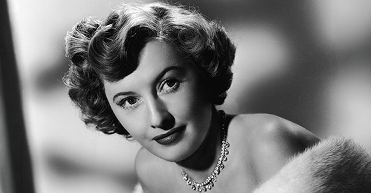 Studio portrait of actor Barbara Stanwyck wearing a fur coat and diamond necklace,1949