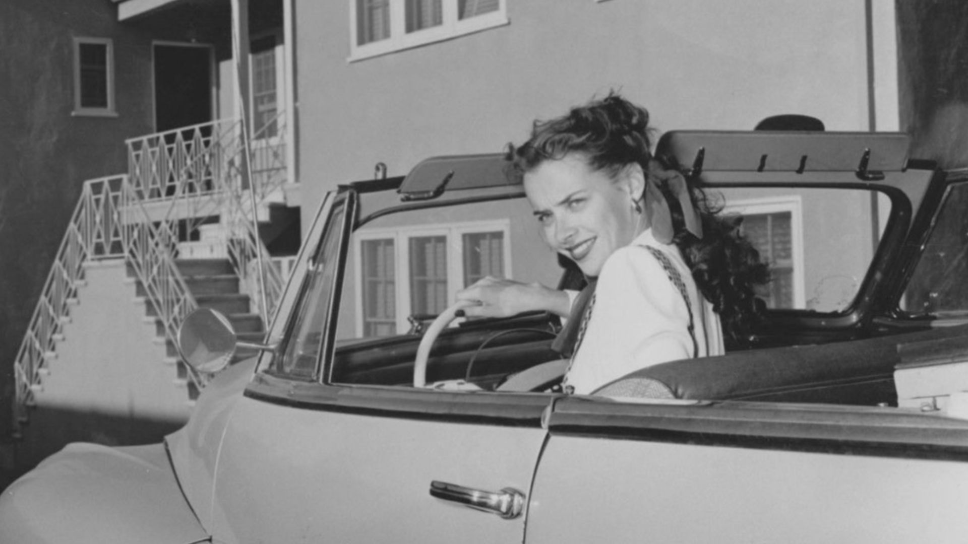 Susan Peters driving in October 1947; press statement reveals her car was refitted with a hand-gear accelerator and brakes to accommodate her in light of her paralysis.