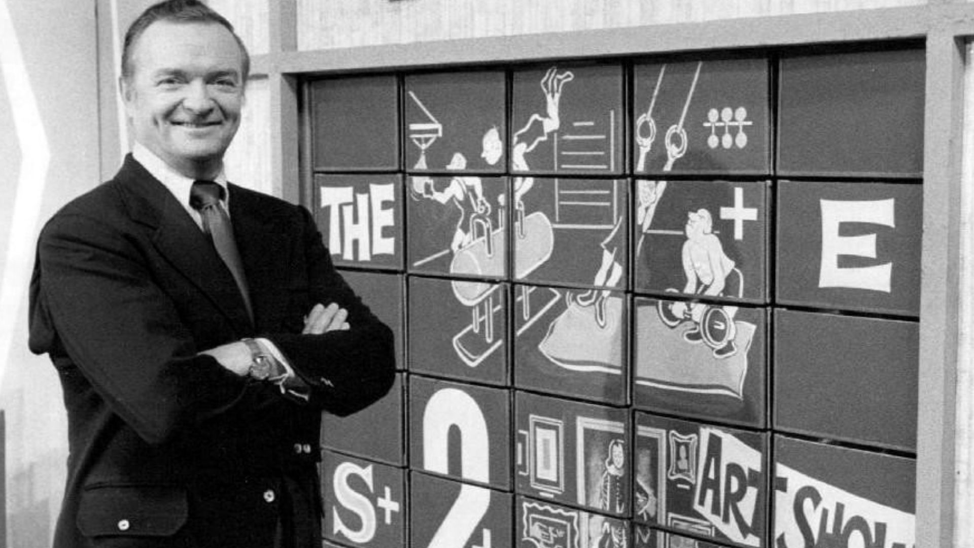 Publicity photo of host Bob Clayton and the game board of the television program Concentration.  The game was played by contestants making matches to uncover portions of the board which displayed a rebus which, when solved, won the round.  The rebus in th