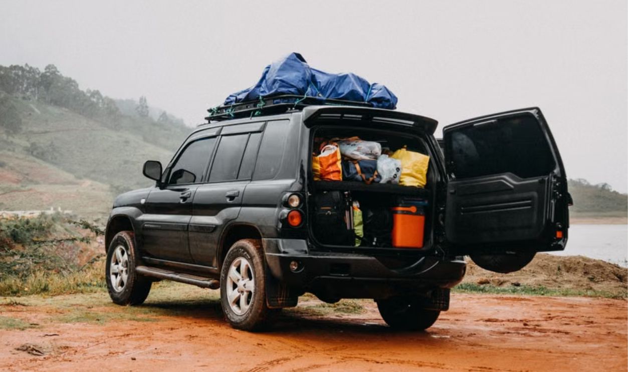 Man prepares for a foggy countryside adventure trip with a packed SUV.
