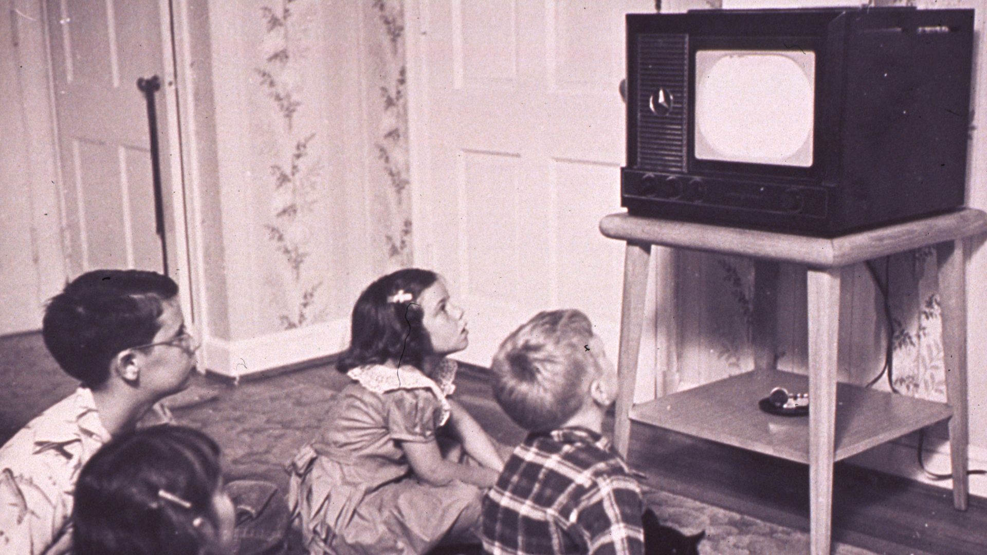 a group of children sitting on the floor in front of a tv