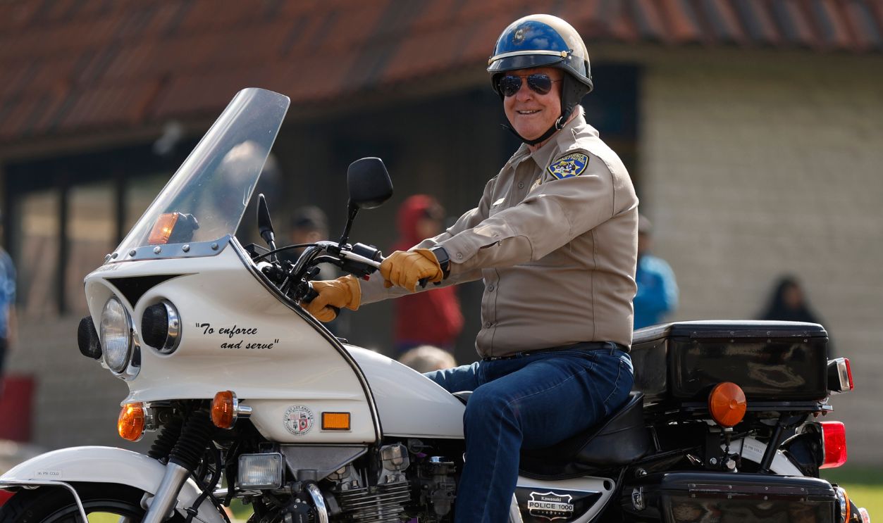 Actor Larry Wilcox, known for his role as California Highway Patrol officer Jon Baker in the television series CHiPs, rides a motorcycle while participating in the Conejo Valley Parade on May 5, 2024 in Thousand Oaks, California