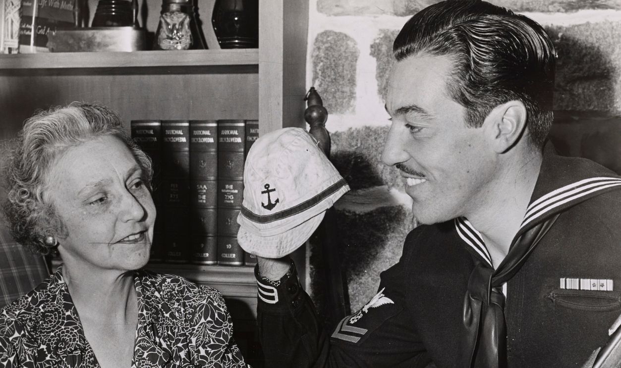 Retired singer Maria Romero (nee Mantillo, 1880 - 1962) smiles as her son, American actor and US Coast Guardsman Cesar Romero (1907 - 1994) shows off his battle souvenirs, 1944. 