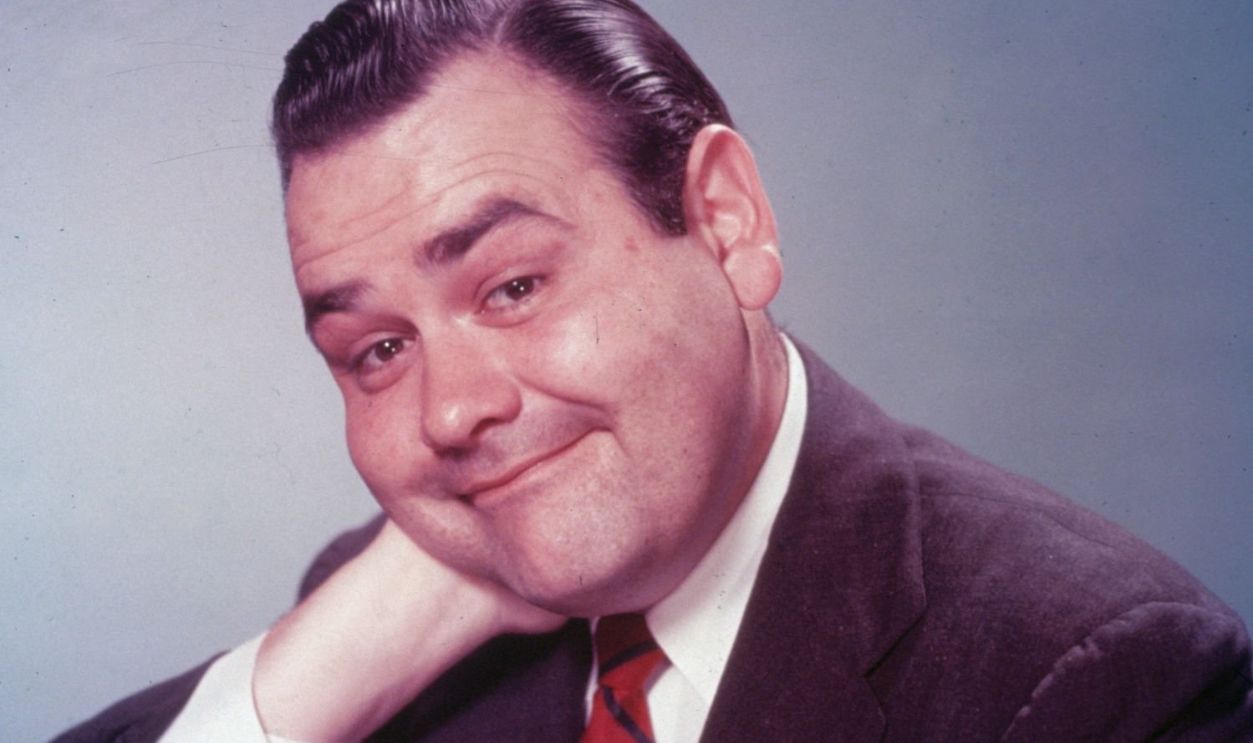 Circa 1955, Studio portrait of a American comedian and actor Jonathan Winters wearing a suit and tie and smiling, 1950s.