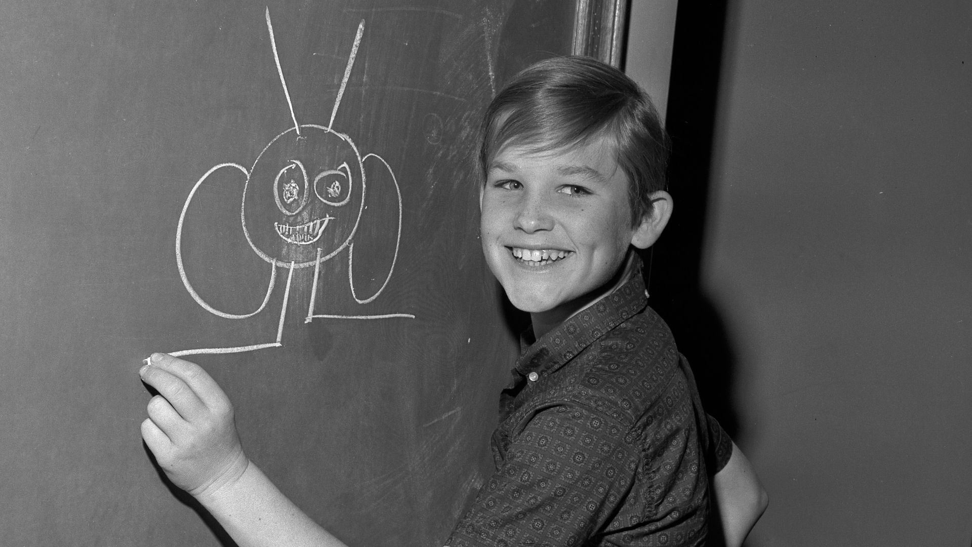 Child actor Kurt Russell drawing on a blackboard while waiting for judge to approve his television contract for the show The Travels of Jaimie McPheeters in Los Angeles