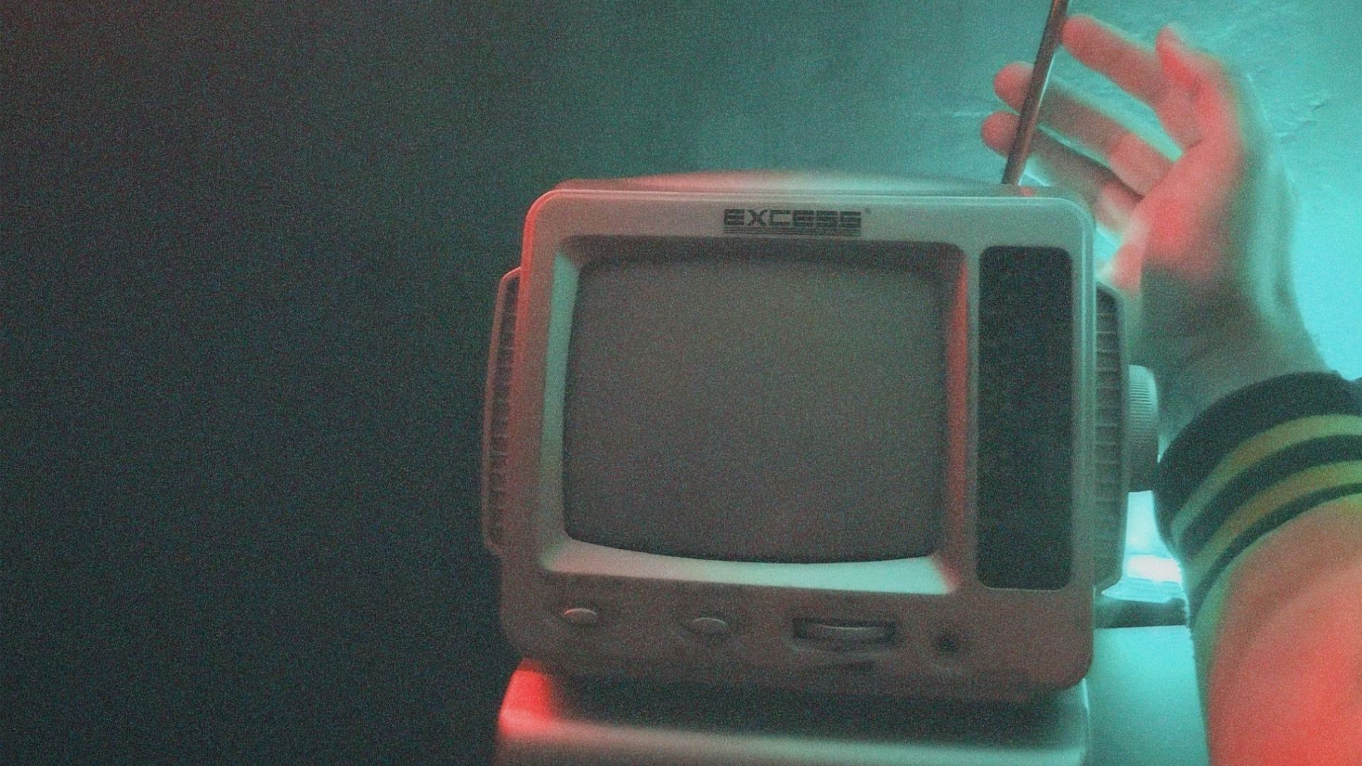 A retro TV set with a hand adjusting the antenna under neon lighting. Vintage ambiance.