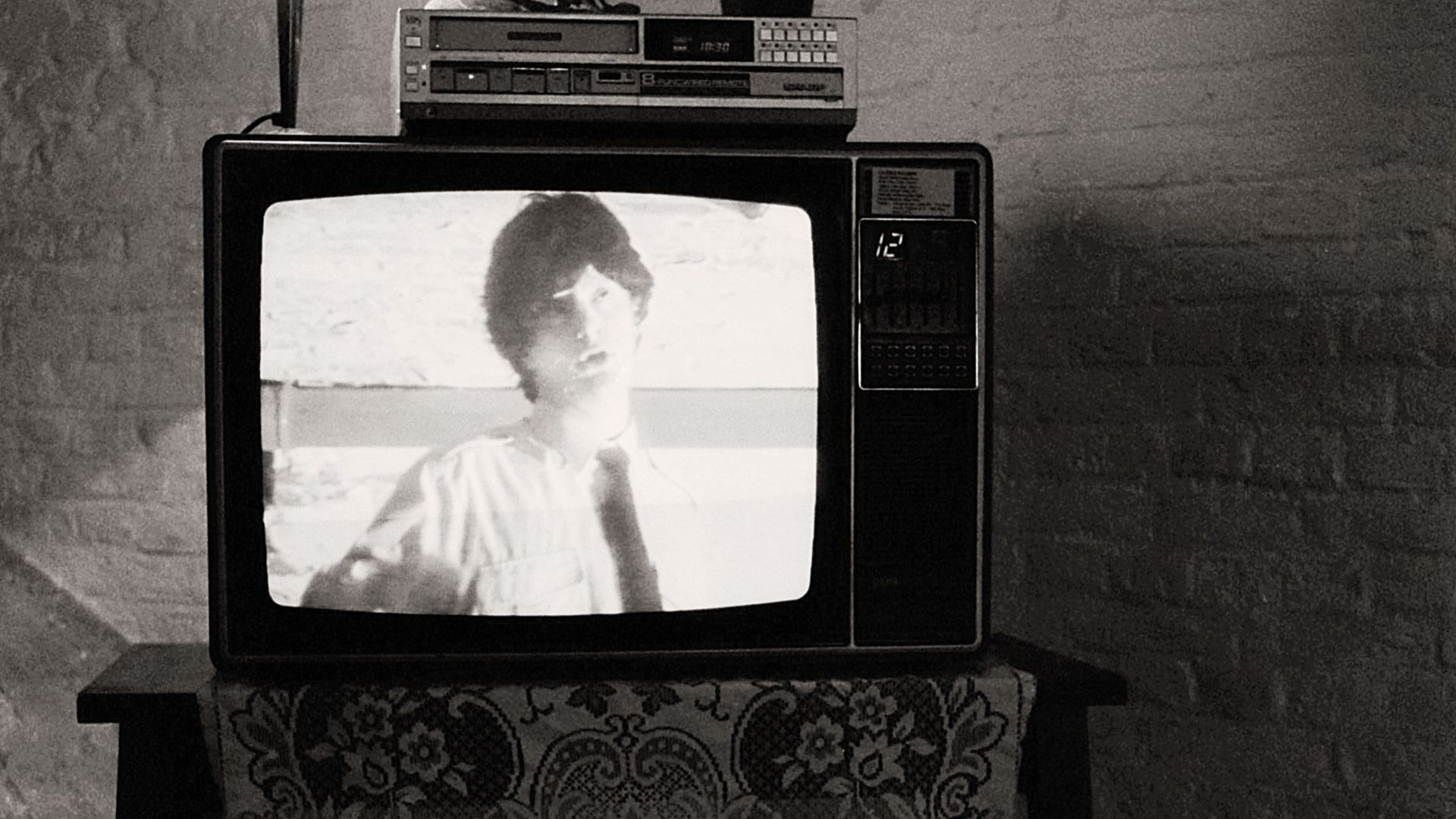 Black and white photo of a retro television in a cozy room with vintage decor.