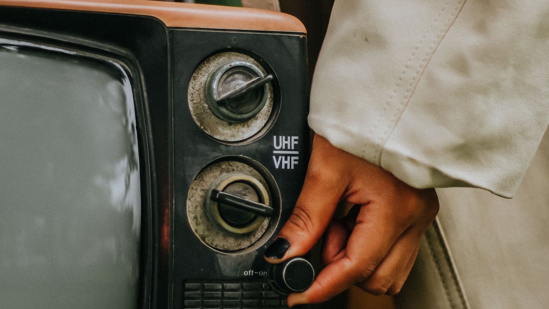 Retro-style image of a person adjusting controls on a vintage television set.