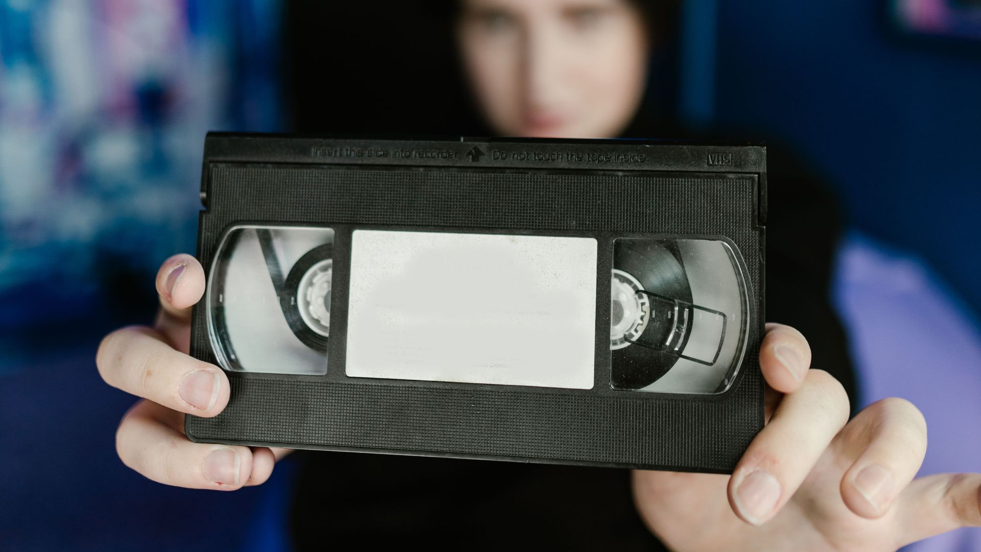 Retro-style image featuring a person holding a VHS tape, emphasizing nostalgia and vintage technology.