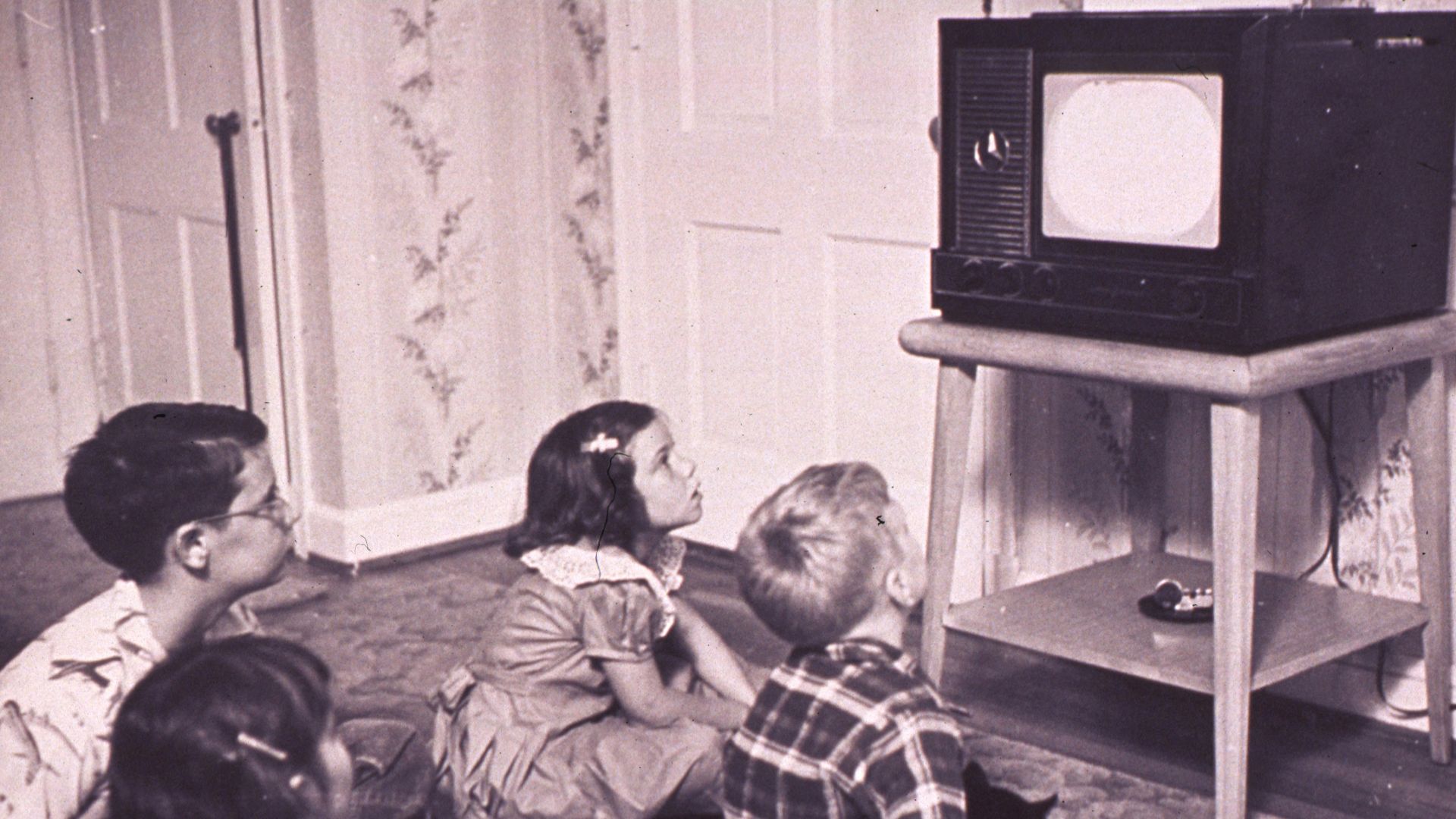 a group of children sitting on the floor in front of a tv