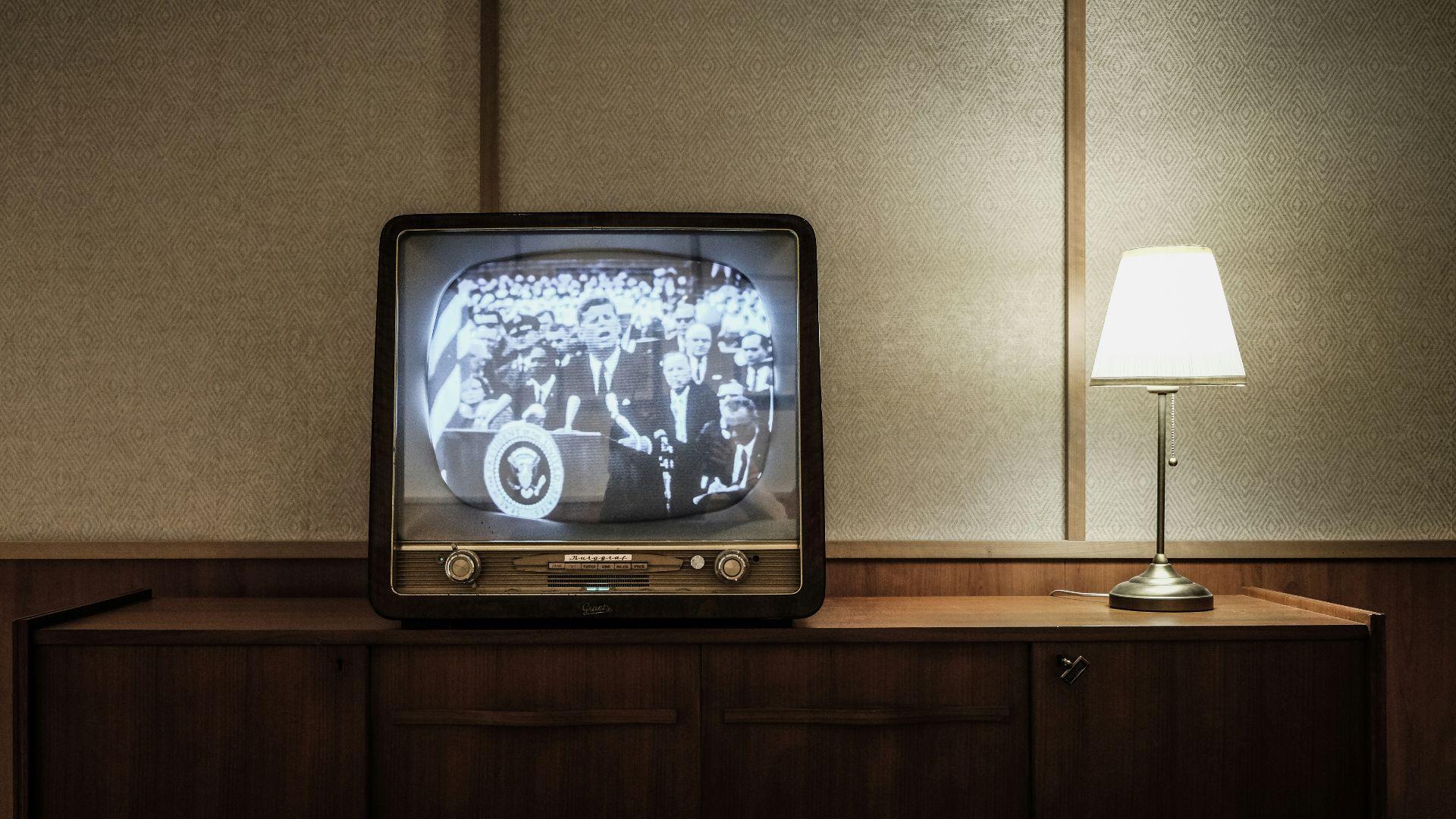 vintage black CRT TV turned-on near lighted table lamp