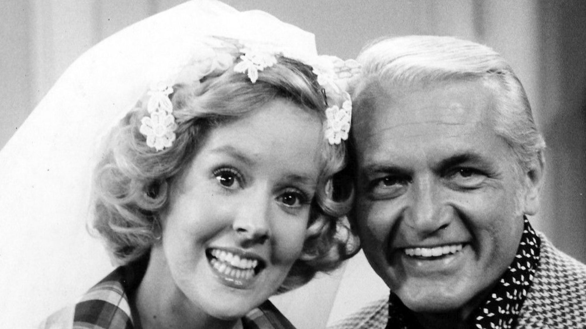 Photo of Georgia Engel and Ted Knight from the television program The Mary Tyler Moore Show.  Georgette Franklin (Engel) and anchorman Ted Baxter (Knight) have just been married at an impromptu ceremony at Mary Richard's (Tyler Moore) apartment.