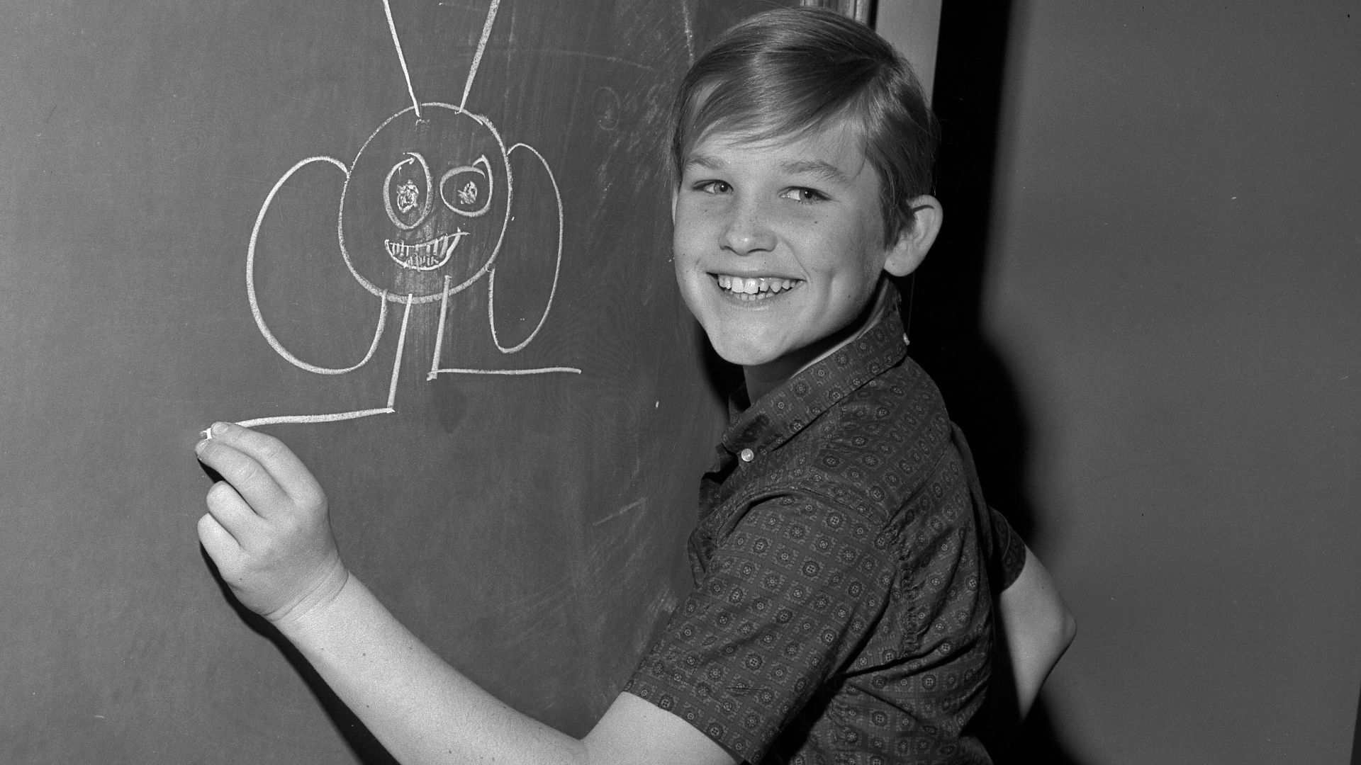 Child actor Kurt Russell drawing on a blackboard while waiting for judge to approve his television contract for the show The Travels of Jaimie McPheeters in Los Angeles