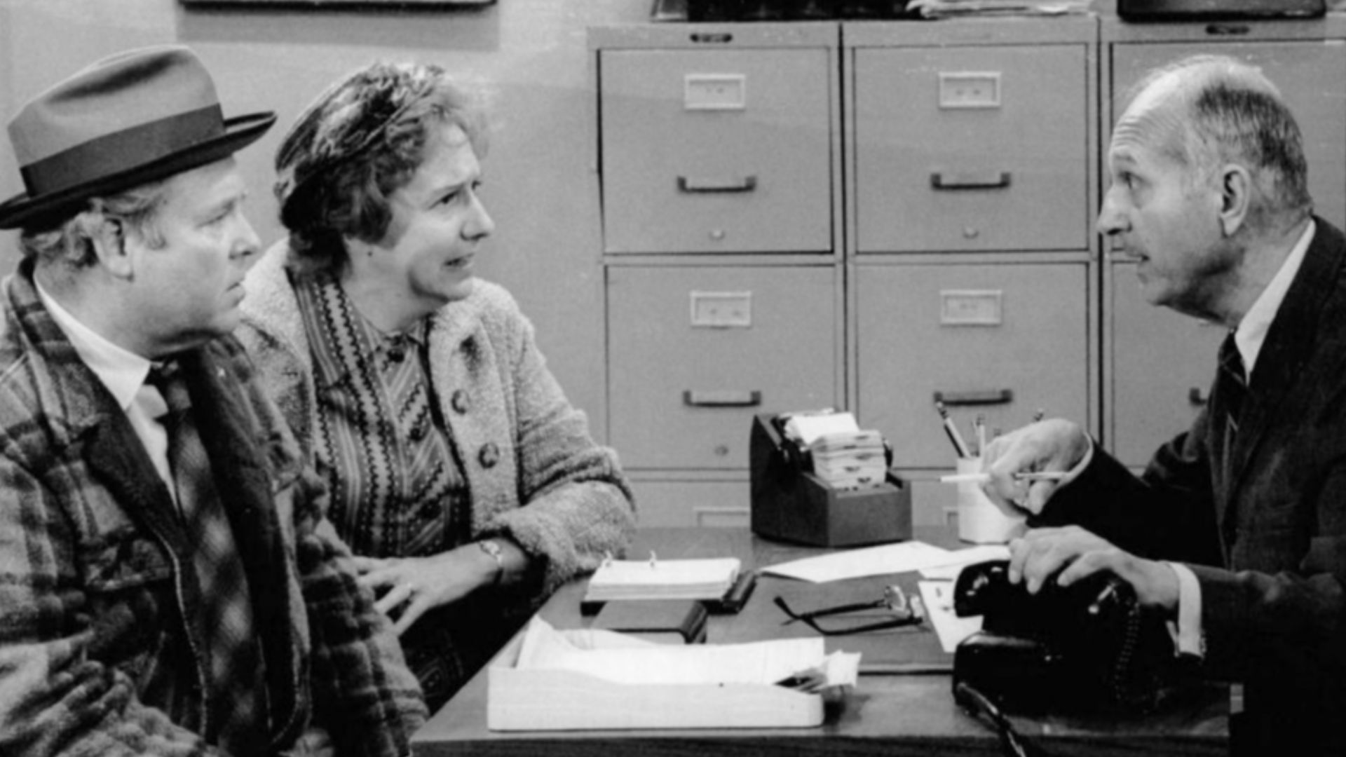 Publicity photo of Carroll O'Connor and Jean Stapleton as Archie and Edith Bunker and guest star James O'Reare as the government official.  In this 27 October 1973 episode, the Bunkers try to convince the government that its computers are wrong; Archie is