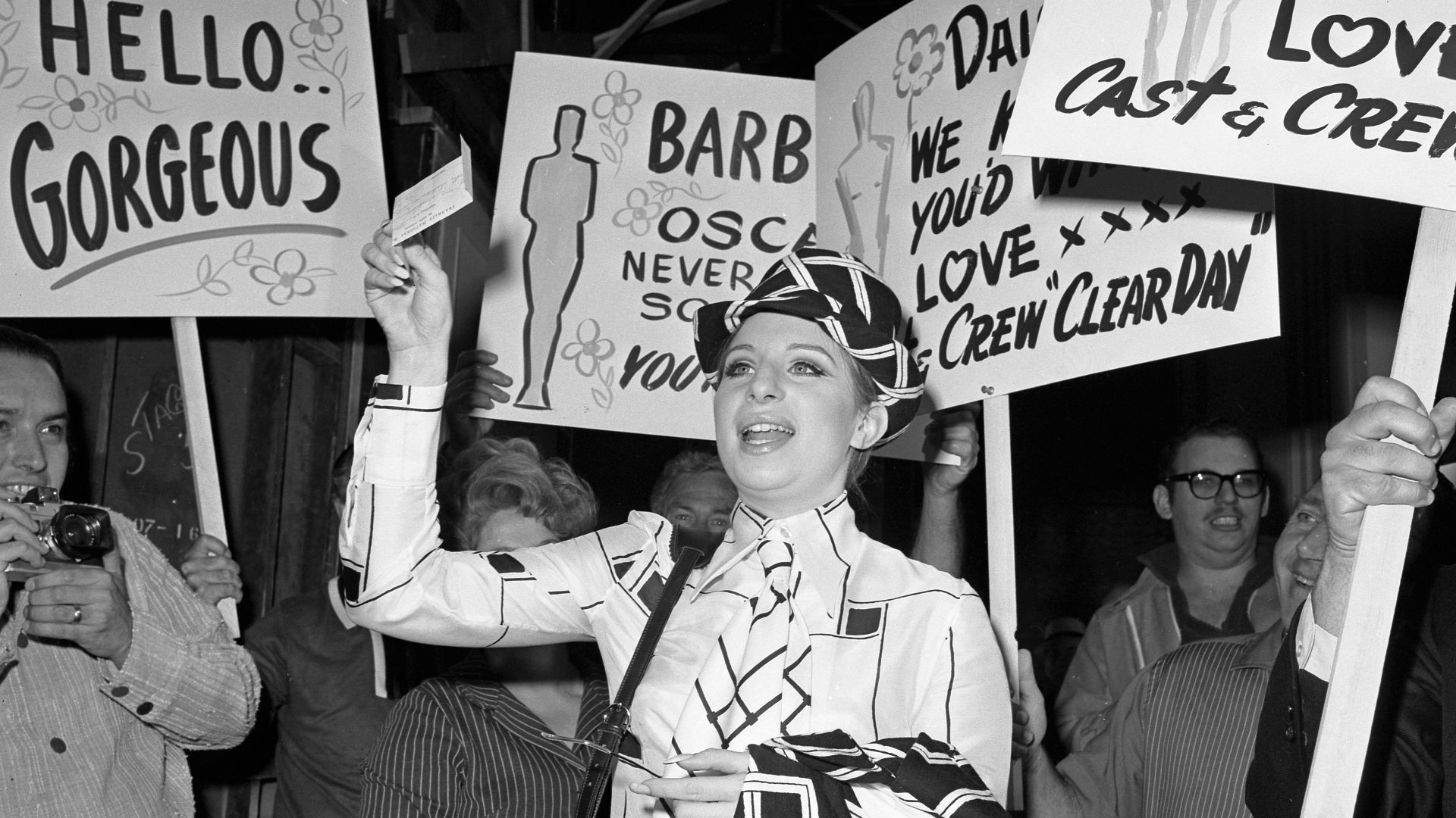 Workers at Paramount Studio greet Barbra Streisand with congratulatory signs as she reports for work on the set of Clear Day. She won an Oscar the previous night for her performance in Funny Girl.