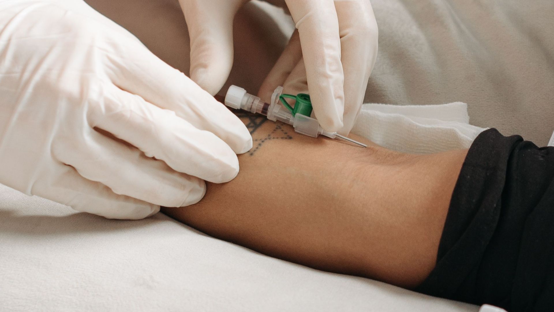 Doctor wearing gloves giving an injection to a patient's arm in a medical setting.