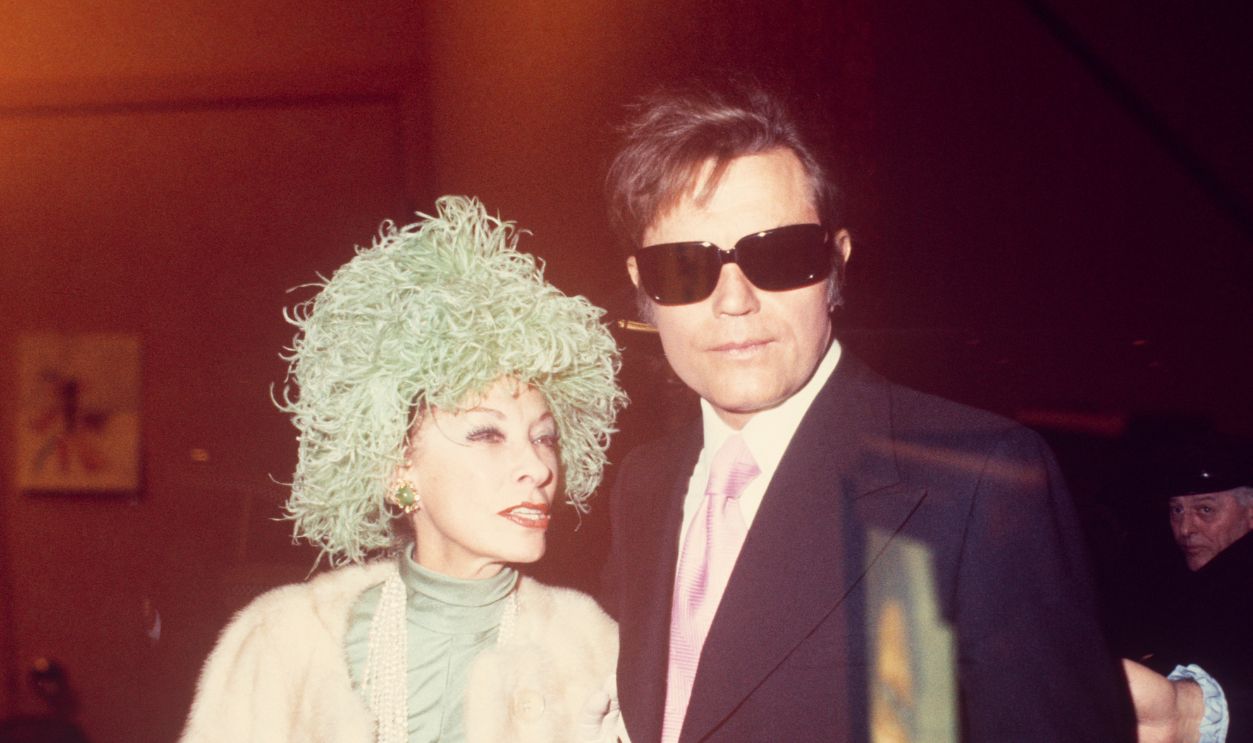 Getty Images - 529346765 - Jack Lord, in sunglasses, with his wife Marie de Narde, shot through a window; circa 1970; New York.