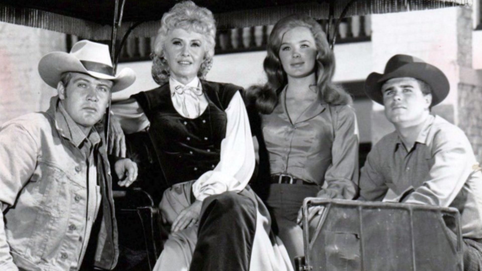 Cast photo from the television program The Big Valley.  From left: Lee Majors (Heath Barkley), Barbara Stanwyck (Victoria Barkley), Linda Evans (Audra Barkley), Charles Briles (Eugene Barkley).  Briles' character appeared only a few times in the first sea