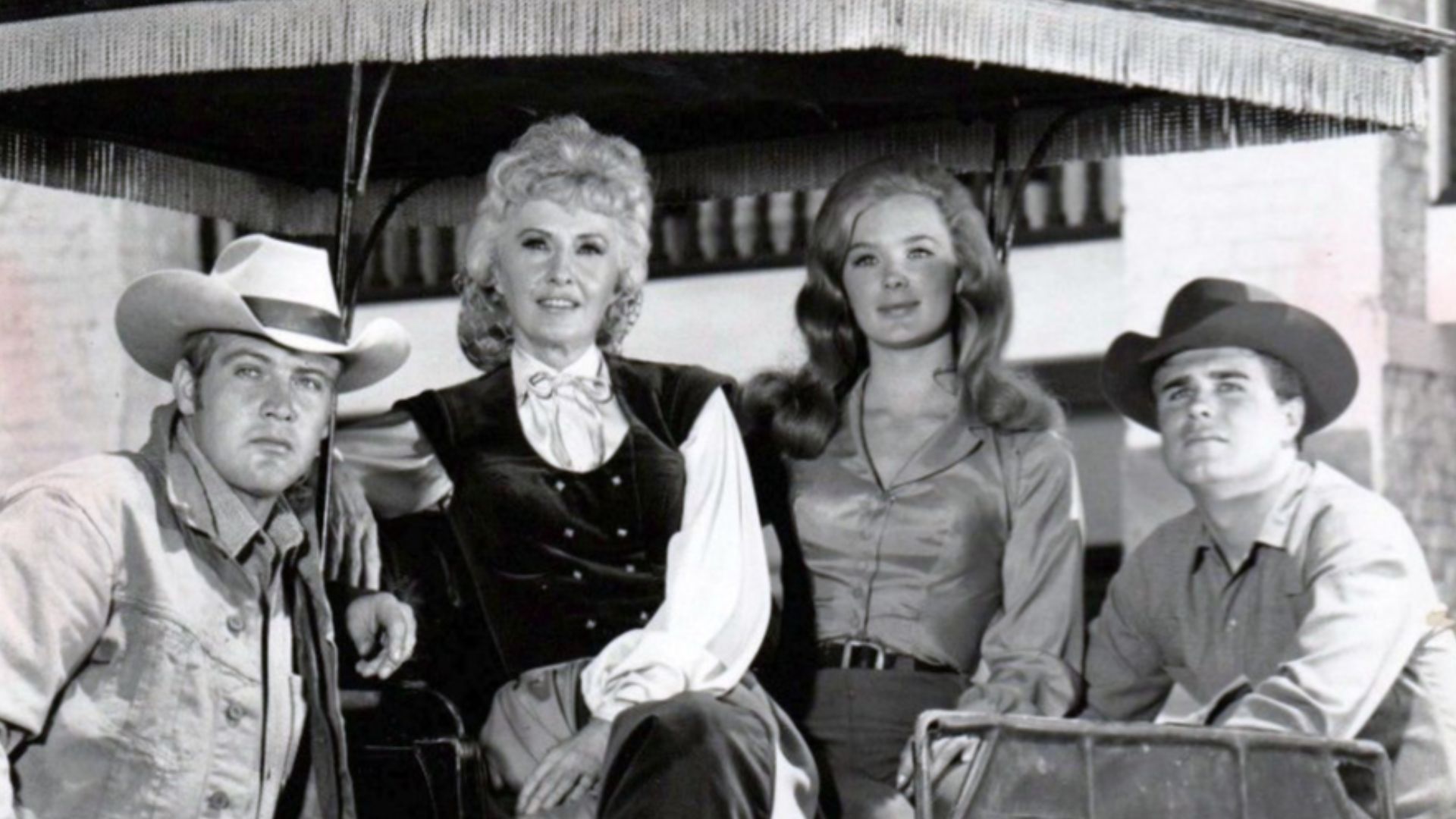 Cast photo from the television program The Big Valley.  From left: Lee Majors (Heath Barkley), Barbara Stanwyck (Victoria Barkley), Linda Evans (Audra Barkley), Charles Briles (Eugene Barkley).  Briles' character appeared only a few times in the first sea