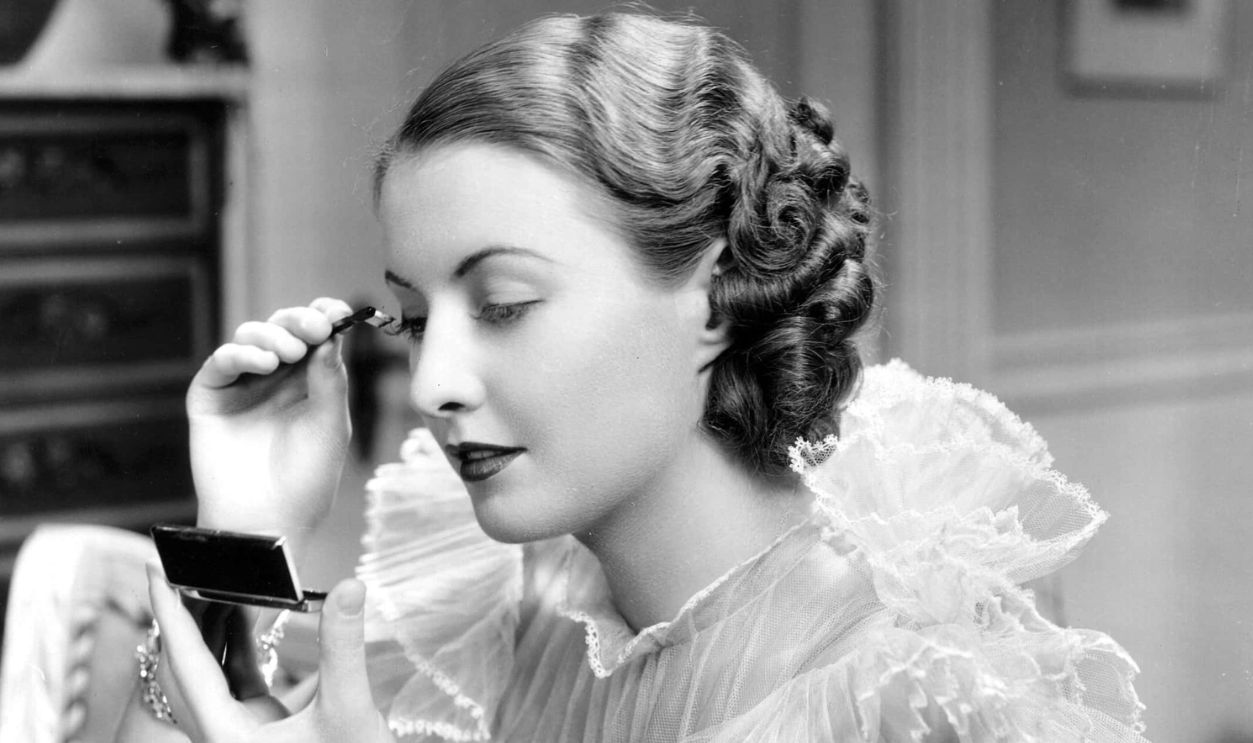 Barbara Stanwyck putting makeup on mirror