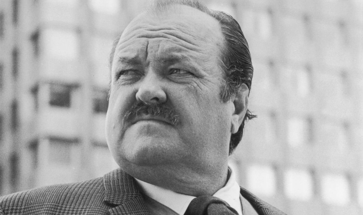 circa 1975: Low-angle image of American actor William Conrad (1920 - 1994) standing outdoors with his thumbs in his vest pockets.