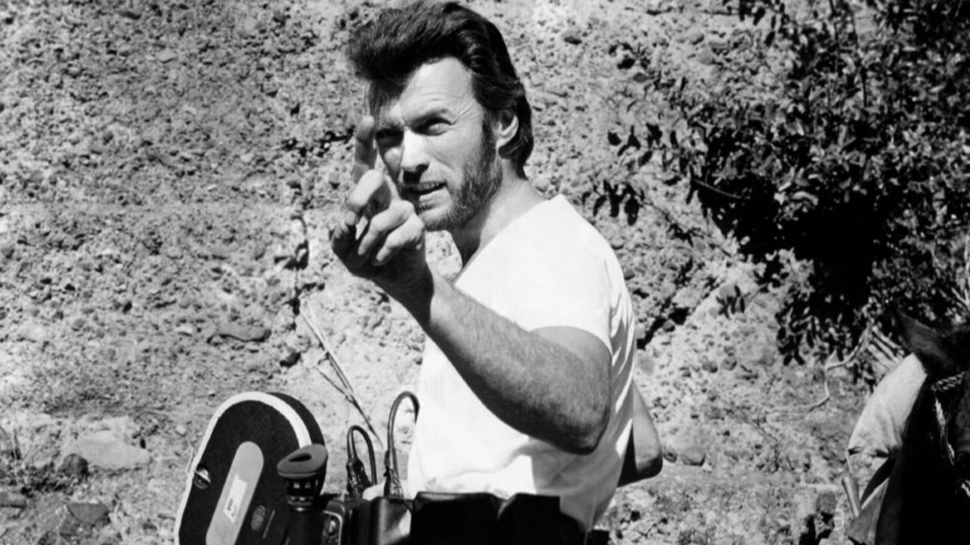 Photograph of Clint Eastwood with a camera during production of the 1970 film Two Mules for Sister Sara, directed by Don Siegel. The film was shot in Mexico in 1969. According to the original caption attached to the backside of the photograph: