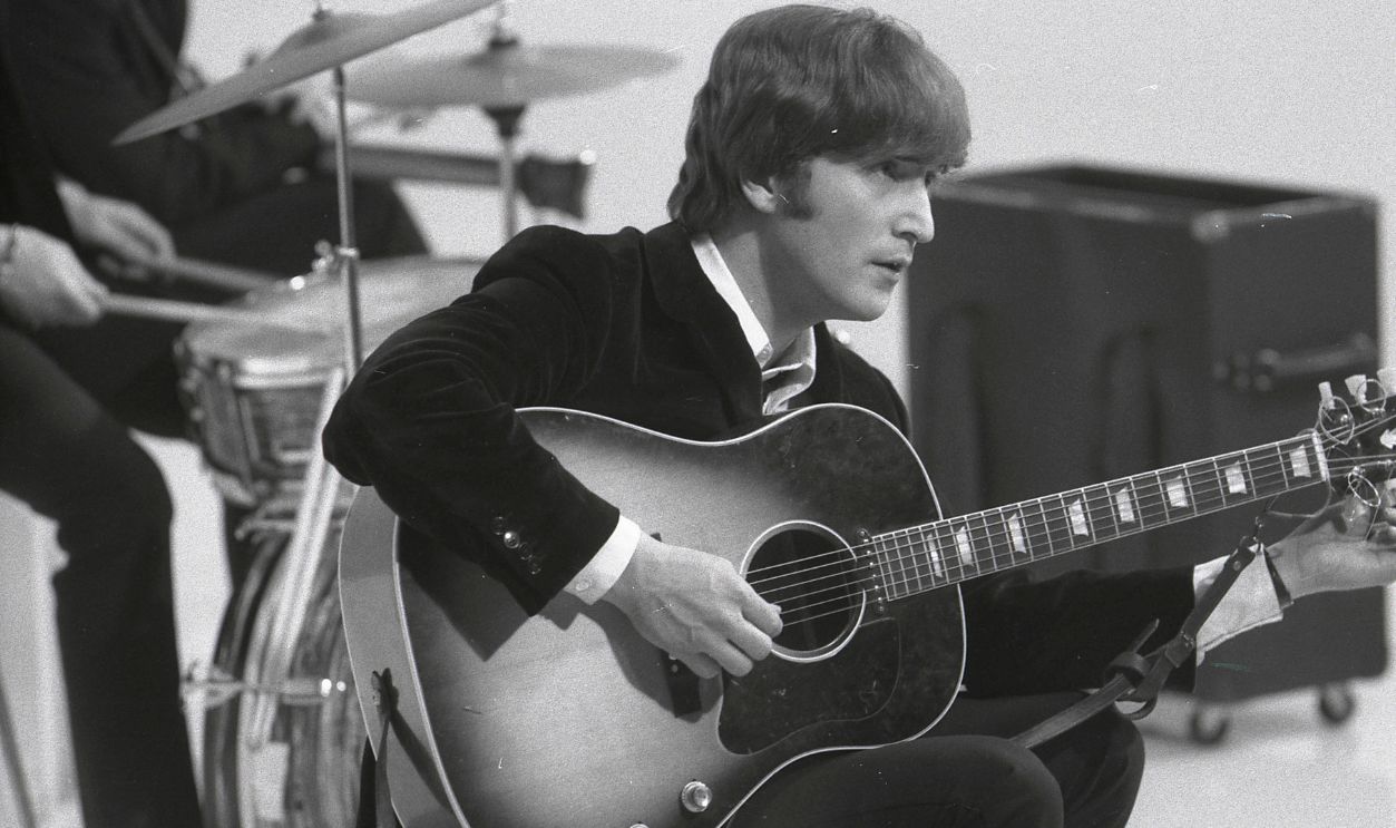 Photo of BEATLES and John LENNON; of the Beatles, tuning guitar (Gibson J160E acoustic) during the filming of 