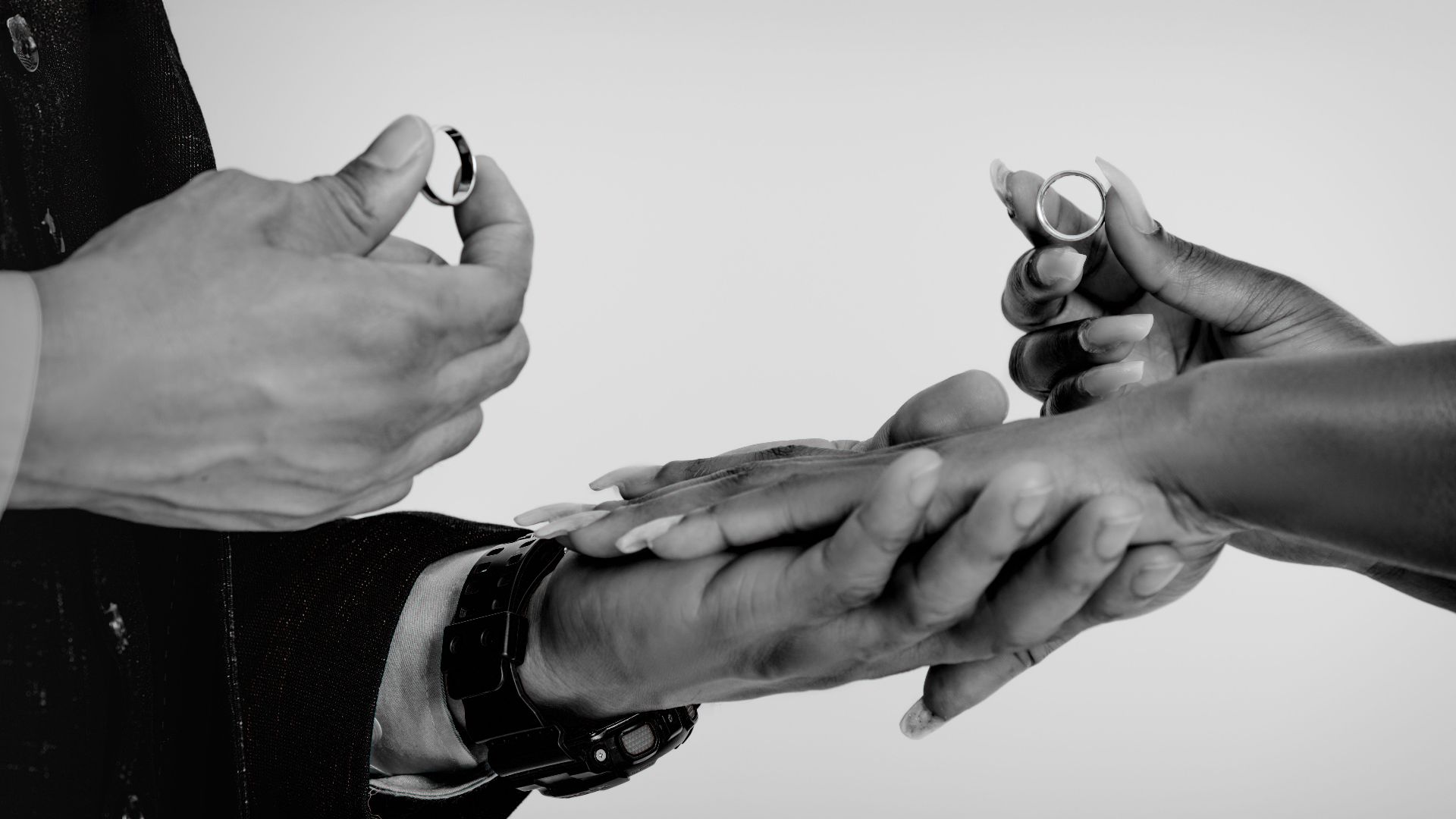 Close-up of hands exchanging wedding rings, symbolizing commitment and love.