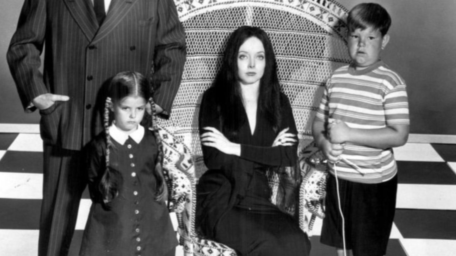 Photo of the main cast of the television program The Addams Family.  Standing back from left—John Astin (Gomez), Ted Cassidy (Lurch).  Standing, front—Lisa Loring (Wednesday), Ken Weatherwax (Pugsley). Seated-Carolyn Jones (Morticia).