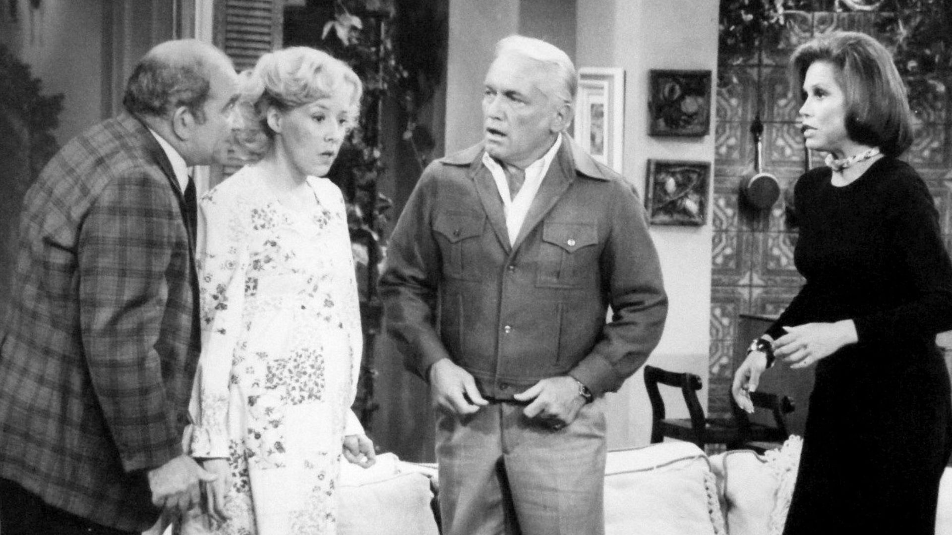 Photo from The Mary Tyler Moore Show.  Mary gives a dinner party that winds up as a birthday party when Georgette Baxter goes into labor during the dinner.  From left: Ed Asner (Lou Grant), Georgia Engel (Georgette Baxter), Ted Knight (Ted Baxter) and Mar