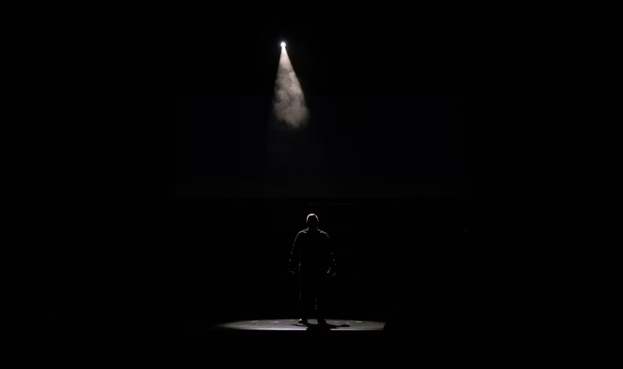 Male Preacher alone on Stage with Overhead Lighting