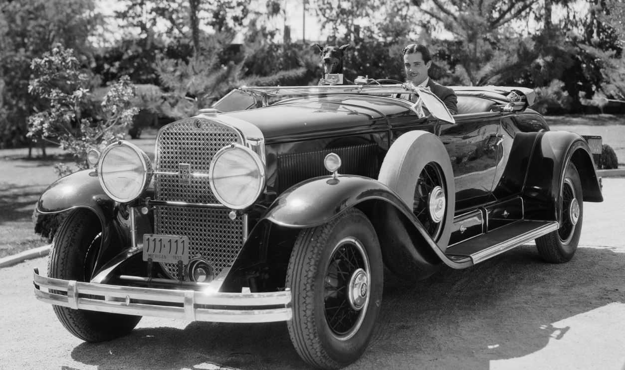 Mexican actor Ramon Novarro (1899 - 1968), takes his dog for a drive in his Cadillac convertible.