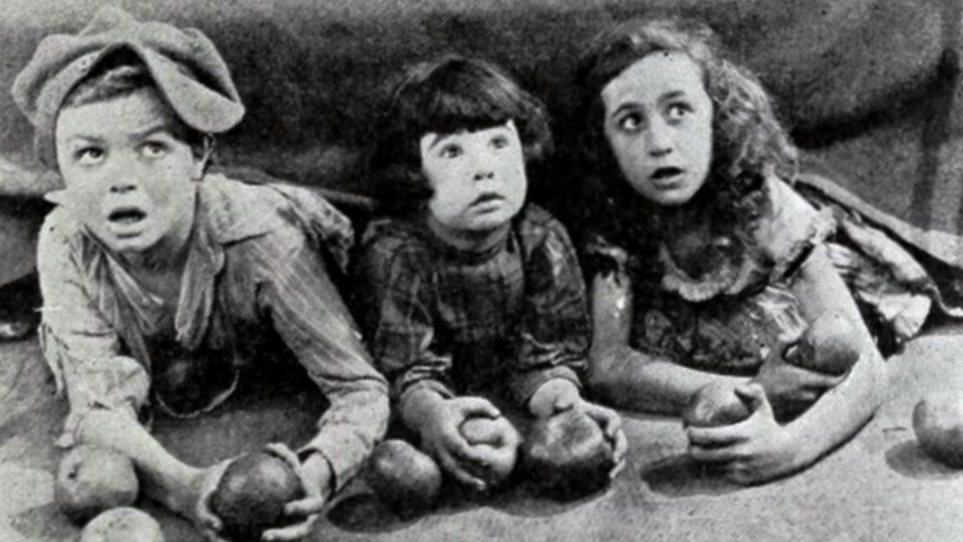 Still from the American drama film The Family Secret (1924) with John Hatton (1913 – 1998), Diana Serra Cary aka Baby Peggy, and an unidentified child actress, on page 11 of the November 17, 1923 Universal Weekly. The still was captioned under the film's 