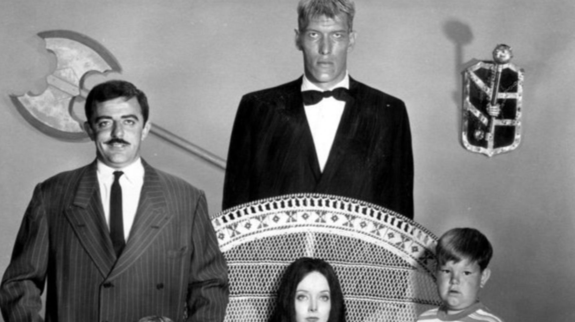 Photo of the main cast of the television program The Addams Family.  Standing back from left—John Astin (Gomez), Ted Cassidy (Lurch).  Standing, front—Lisa Loring (Wednesday), Ken Weatherwax (Pugsley). Seated-Carolyn Jones (Morticia).