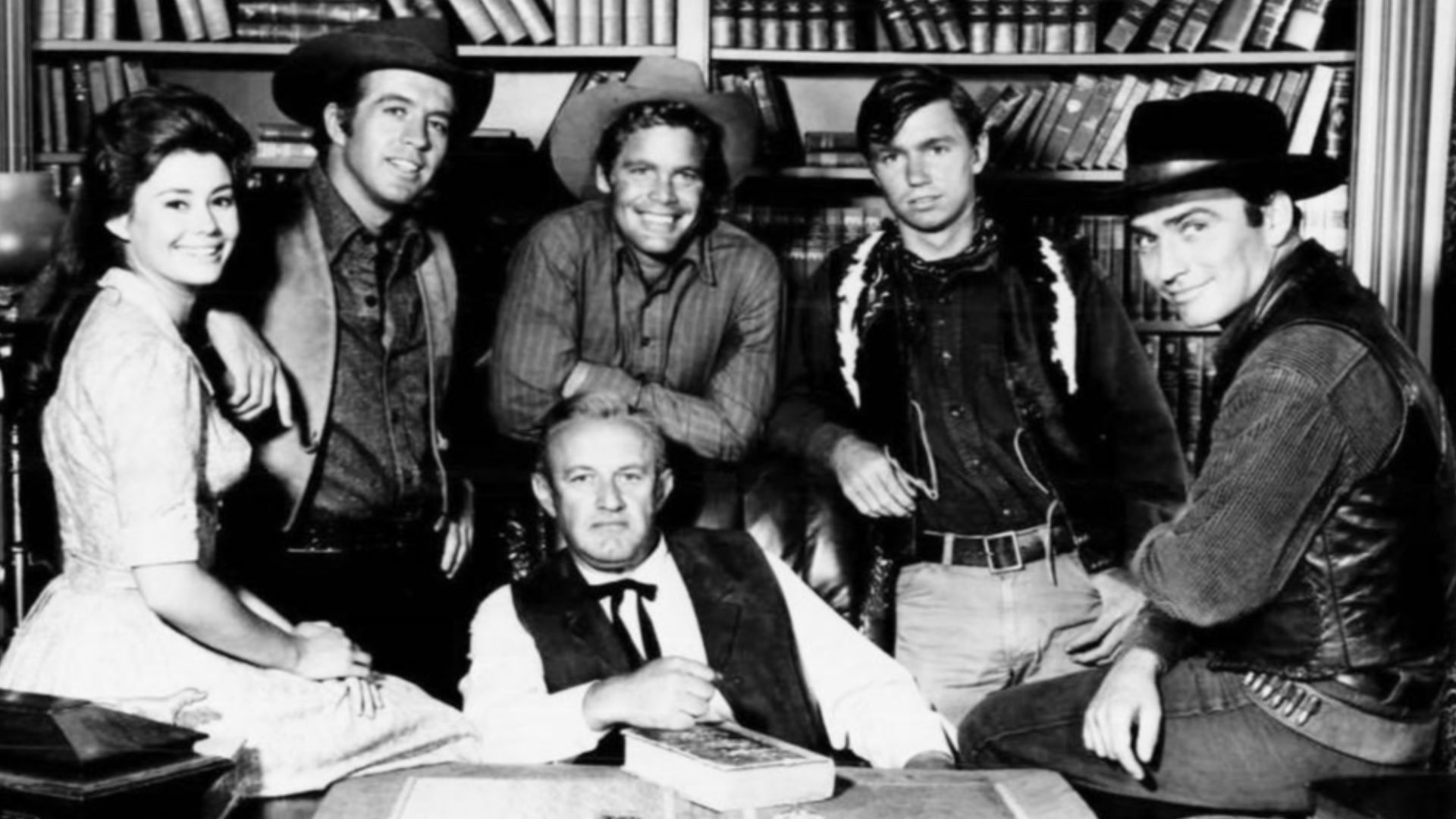 Cast photo from the television program The Virginian.  Center: Lee J. Cobb (Judge Garth).  From left: Roberta Shore (Betsy Garth), Clu Gulager (Emmett Ryker), Doug McClure (Trampas), Randy Boone (ranch hand), James Drury (The Virginian).