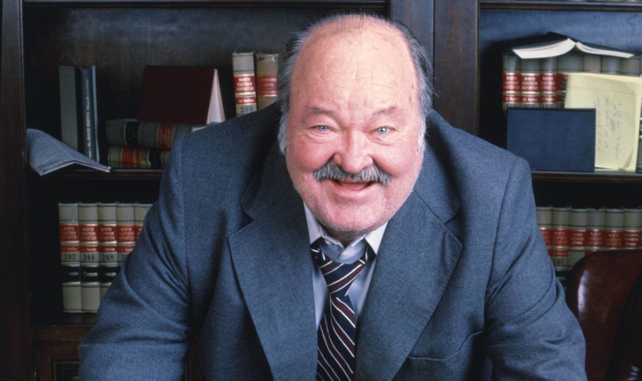 William Conrad (1920-1994), US actor, leaning on a desk on which sits an Englisg bulldog, in a publicity portrait issued for the US television series, 'Jake and the Fatman', circa 1990. The crime drama starred Conrad as 'Jason Lochinvar 'Fatman' McCabe'. 