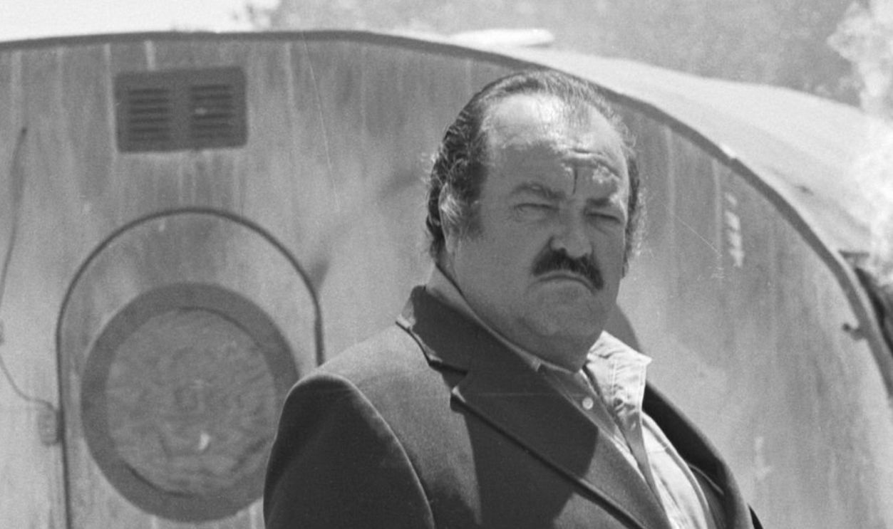 Promotional portrait of American actor William Conrad (1920 - 1994) as Frank Cannon, as he poses in front of a flaming mobile home for the television detective series 'Cannon,' July 3, 1972.