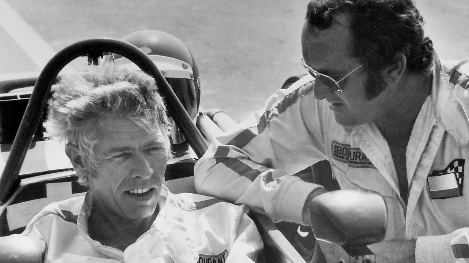 Photo of Bob Bondurant teaching actor James Coburn how to drive a race car.