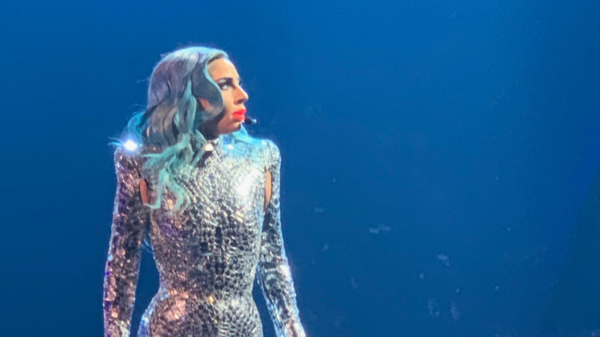 Lady Gaga on stage in a sequined bodysuit looking away from the camera.